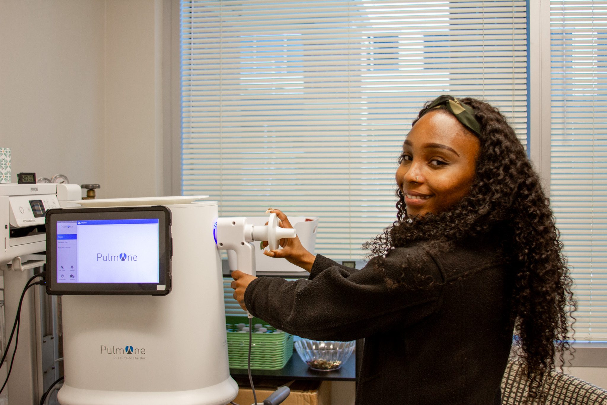 Technician performing a pulmonary function test using a spirometry machine in a clinic setting